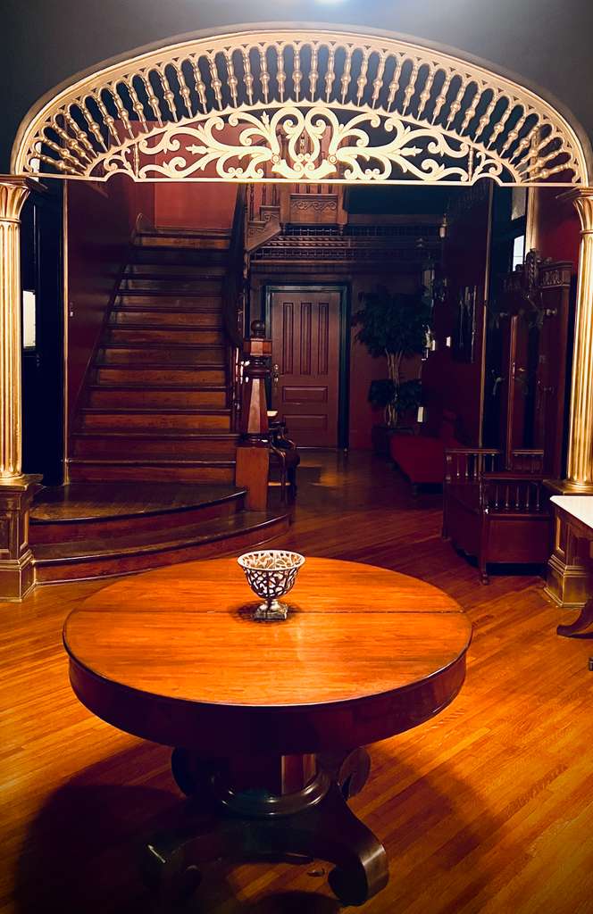 The Continental Cigar Club ambience — a cigar resting on a Continental-branded leather case beside a crystal whiskey glass on a polished bar, set against the warm glow of the lounge